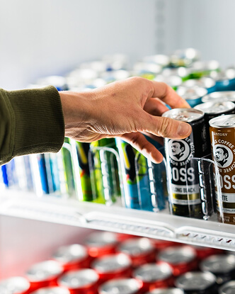 Hand reaching for a canned drink in a fridge