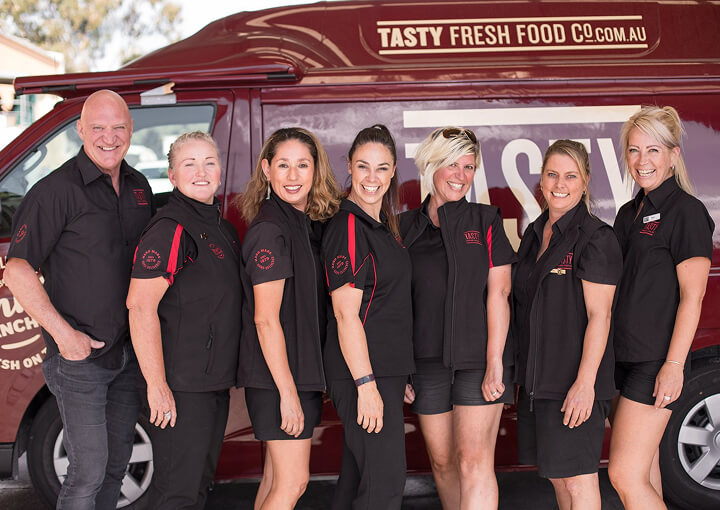 Group of Tasty Fresh Food Co staff smiling beside a company van