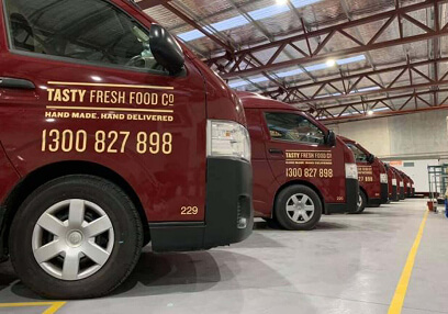 Tasty Fresh Food Co vans lined up inside a warehouse